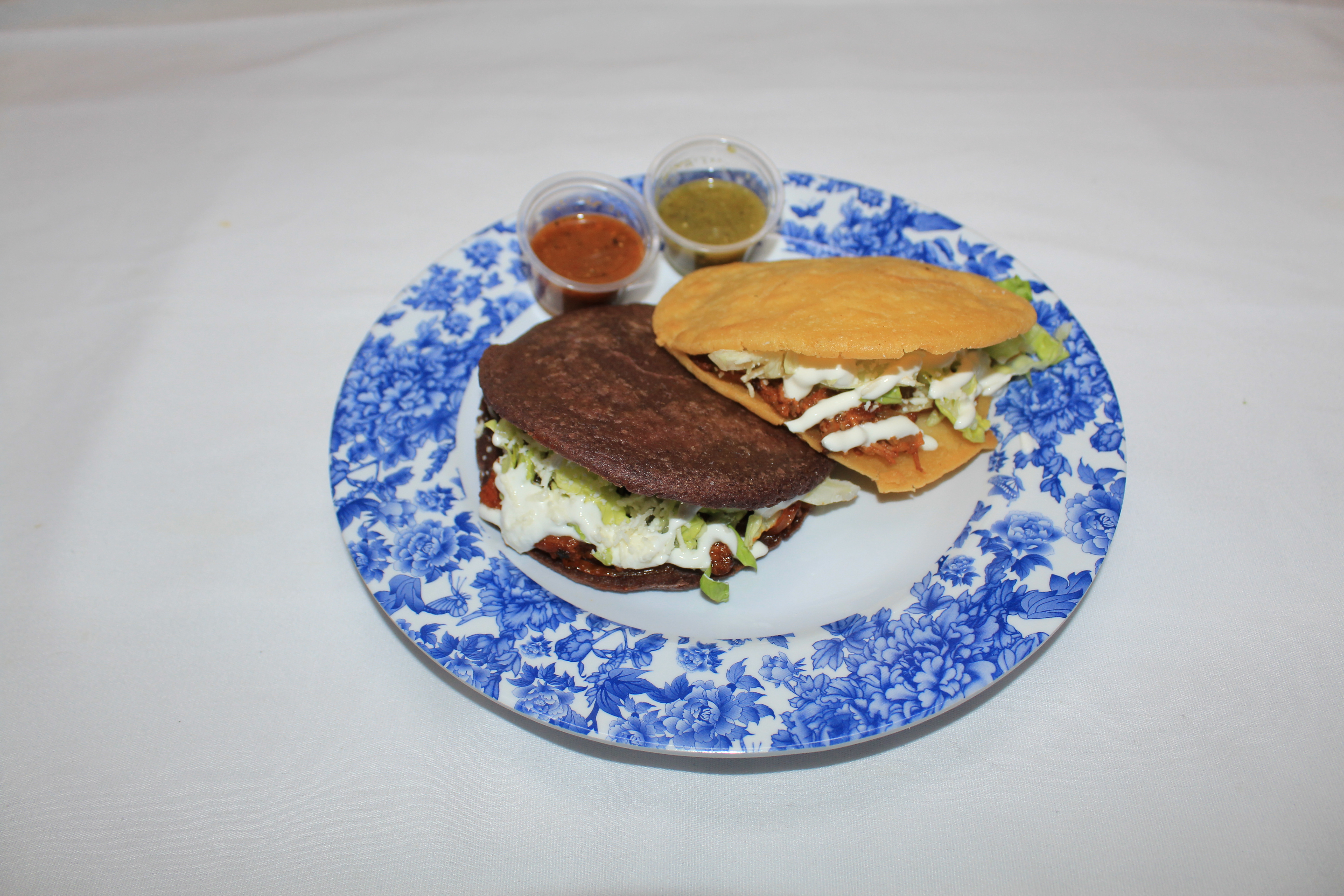 one blue corn and yellow corn gordita on plate with salsa